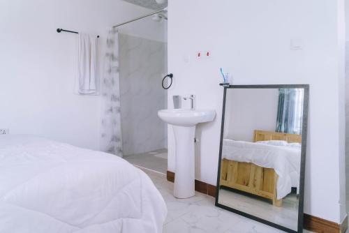 a white bedroom with a sink and a mirror at Ambokili Farm Country House in Kimana