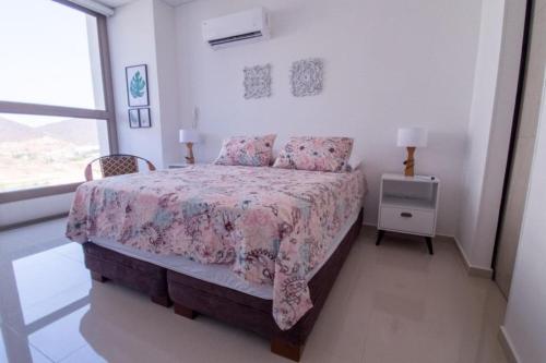 a white bedroom with a bed and a window at Samaria Club de Playa, apto 910 in Santa Marta