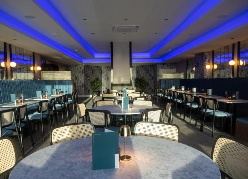 ein Restaurant mit Tischen, Stühlen und blauen Lichtern in der Unterkunft Marian Resort And Spa in Prestatyn