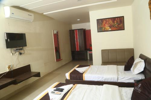 a hotel room with two beds and a flat screen tv at Park Niveda in Shamshabad