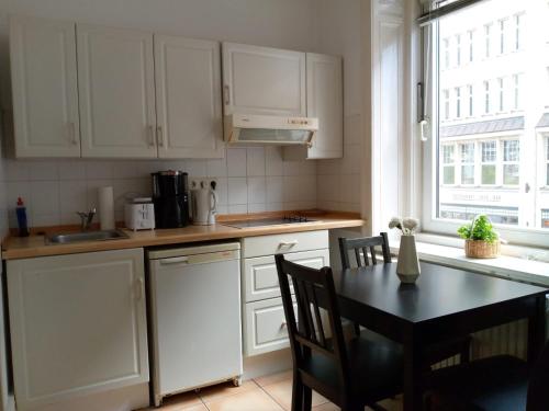 une cuisine avec des placards blancs, une table et une fenêtre dans l'établissement Apartments City Center 8, à Hambourg
