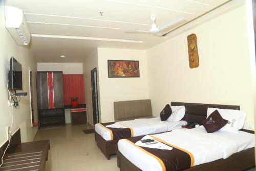 a hotel room with two beds and a television at Park Niveda in Shamshabad
