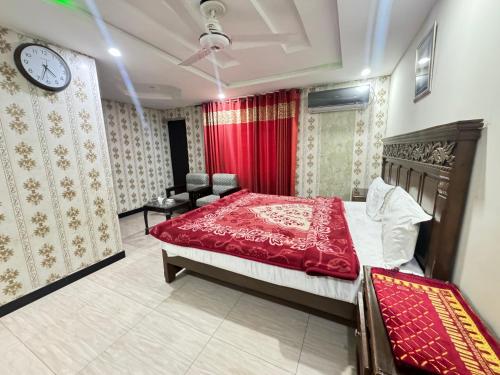 ein Schlafzimmer mit einem Bett und einer Uhr an der Wand in der Unterkunft Millat Hotel in Islamabad