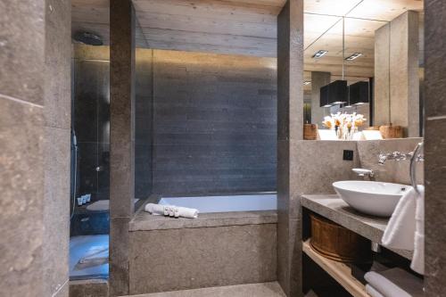 a bathroom with a sink and a bath tub at L'Alpaga, a Beaumier hotel in Megève