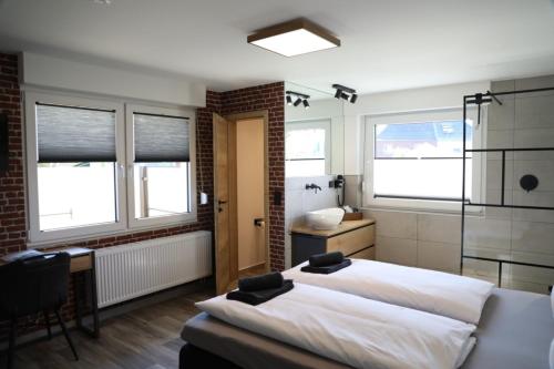 a bedroom with two beds and a bathroom with windows at Hotel Weilerhof in Dormagen