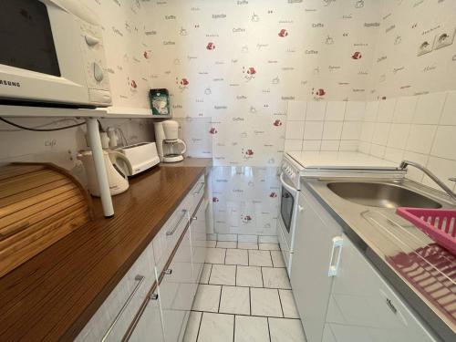 une petite cuisine avec un évier et un micro-ondes dans l'établissement Bel Appartement T2 à 100m de la Plage avec Parking Privatif - FR-1-324A-40, à Saint-Hilaire-de-Riez