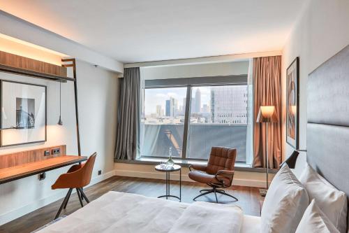 a hotel room with a bed and a desk and a window at Radisson Blu Hotel Frankfurt in Frankfurt