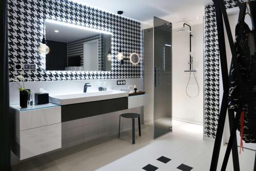ein Bad mit einem Waschbecken, einem Spiegel und einer Dusche in der Unterkunft Radisson Blu Hotel Frankfurt in Frankfurt am Main