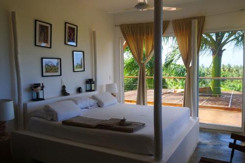 - une chambre avec un grand lit blanc et une grande fenêtre dans l'établissement Villa Mata De Mango, à El Limón