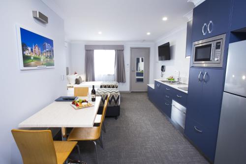 a blue and white room with a bed and a kitchen at Altitude Motel Apartments in Toowoomba