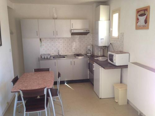 une petite cuisine avec des placards blancs et une table avec des chaises dans l'établissement Appartement F2 avec terrasse, parking et ascenseur - 2/4 pers - Amélie-les-Bains - FR-1-703-47, à Amélie-les-Bains-Palalda