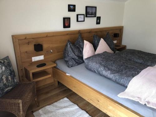a bed with a wooden headboard and pillows on it at Beautiful holiday home near town centre in Reisach