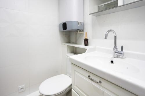a white bathroom with a toilet and a sink at Charming Suite 1bdr Saint Honoré Parisian Escape in the Heart of the City NO ELEVATOR in Paris