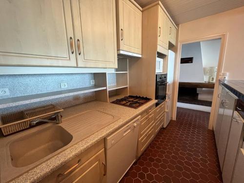 une cuisine avec des armoires blanches, un évier et une cuisinière dans l'établissement Bel Appartement 2 Chambres avec Accès Direct Plage à Saint-Gilles-Croix-de-Vie - FR-1-324-547, à Saint-Gilles-Croix-de-Vie