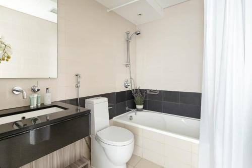 a bathroom with a toilet and a sink and a bath tub at Frank Porter - The Lofts Central in Dubai