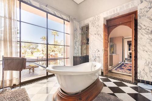 a bathroom with a tub and a large window at Villa May sur le Golf de la Palmeraie with Cooker and Butler included in Marrakech