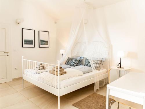 een witte slaapkamer met een hemelbed bij Beautiful Villa Torre II with whirlpool in Tar in Frata