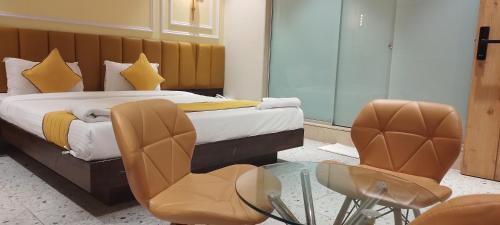Shine Hospitality Group في مومباي: غرفة نوم بسرير وطاولة وكراسي زجاجية