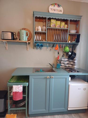 La cuisine est équipée d'un comptoir bleu et d'un évier. dans l'établissement Le chant des oiseaux, à Cambo-les-Bains