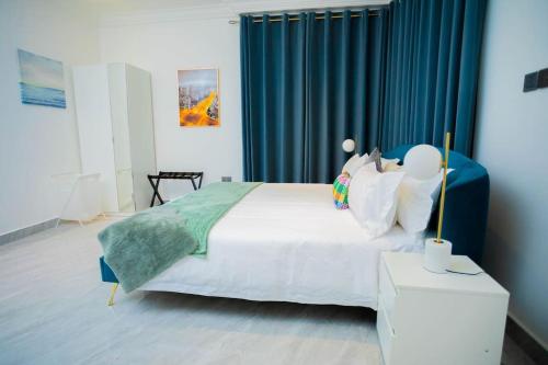 a bedroom with a large bed with blue curtains at The Pearl - Lincoln - 2nd floor in Kumasi
