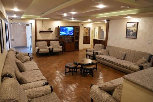 a living room with couches and a flat screen tv at Omayah hotel irbid in Irbid