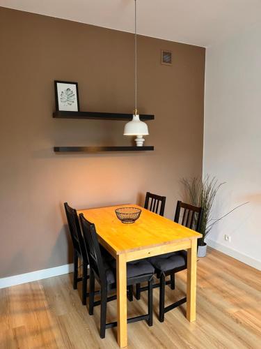 a dining room table with chairs and a clock on the wall at Apartament Gdynia z duszą in Gdynia
