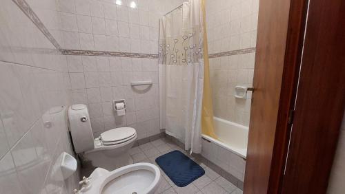 een witte badkamer met een toilet en een douche bij Casa familiar con patio y parrilla in Tandil