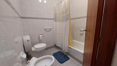 een witte badkamer met toilet en douche bij Casa familiar con parrilla y patio compartido in Tandil