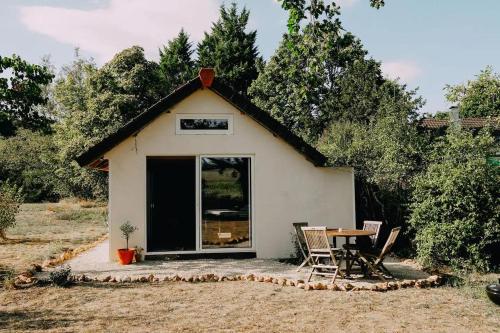 une petite maison blanche avec une table et des chaises dans l'établissement Eco-friendly Welness Tiny House in Liglet, à Liglet