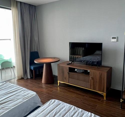 a hotel room with a tv and a table and a bed at Cam Ranh provided by Pearl in Miếu Ông