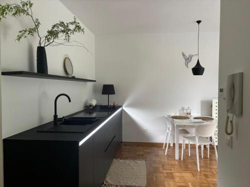 eine Küche mit einem schwarzen Waschbecken und einem Tisch in der Unterkunft Ljubljanica Apartment in Ljubljana