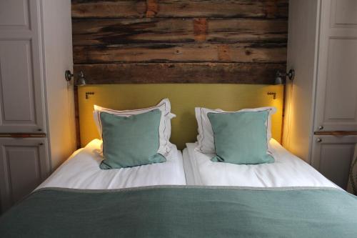 a bed with green and white pillows on it at Olarsgården Hotell in Lindvallen