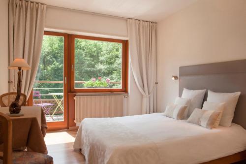 - une chambre avec un lit et une grande fenêtre dans l'établissement La Fischhutte, The Originals Relais (Relais du Silence), à Mollkirch