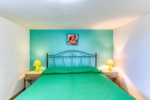 ein Schlafzimmer mit einem grünen Bett mit zwei Nachttischen in der Unterkunft Casa Gianna in Marina di Pescoluse