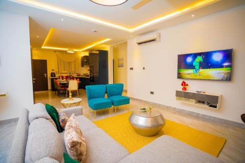 een woonkamer met een bank en een tv aan de muur bij The Pearl - Bountiful - 1st floor in Kumasi