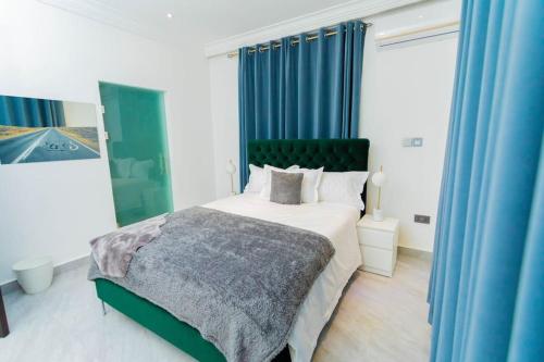 een slaapkamer met een groot bed en blauwe gordijnen bij The Pearl - Bountiful - 1st floor in Kumasi