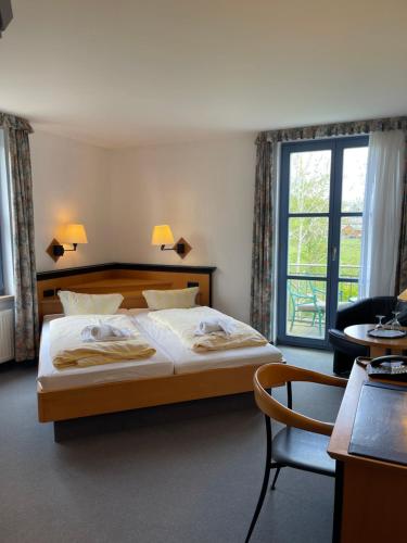 a bedroom with a bed and a chair and a window at Hotel Zur alten Schmiede in Schaprode