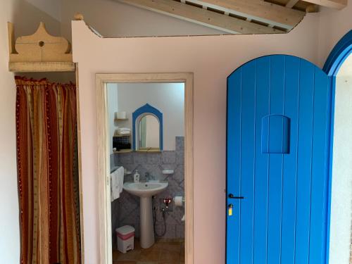 La salle de bains est pourvue d'une porte bleue et d'un lavabo. dans l'établissement Bed & Breakfast Sole Azzurro, à Custonaci