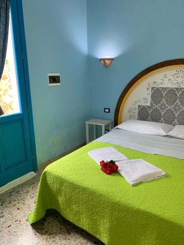 a bedroom with a bed with a green blanket and flowers on it at Bed & Breakfast Sole Azzurro in Custonaci