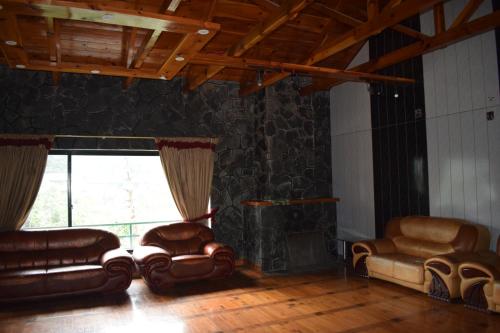 sala de estar con muebles de cuero y ventana grande en Royal House 2, en Nathia Gali