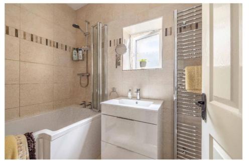 a bathroom with a tub and a sink and a bath tubermottermott at Large Bungalow to sleep up to 8 in Slough
