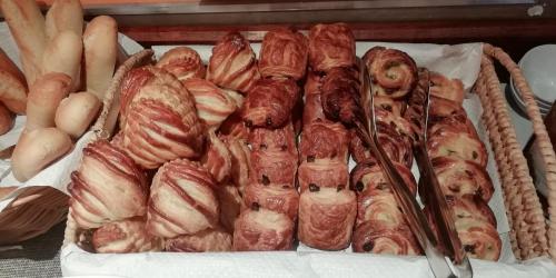 un vassoio di prodotti alimentari con croissant e altri prodotti alimentari di Hôtel Lumières Montmartre Paris a Parigi