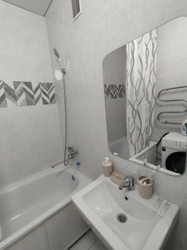 La salle de bains blanche est pourvue d'un lavabo et d'un miroir. dans l'établissement Квартира в новом районе, à Öskemen