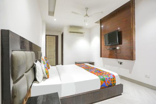 um quarto com uma cama e uma televisão na parede em FabExpress Lotus Palace em Nova Deli