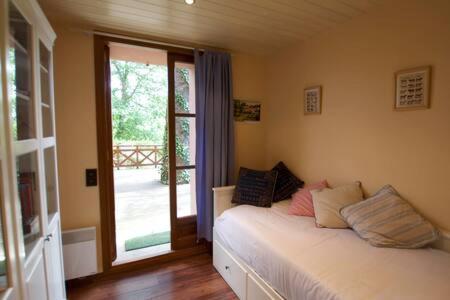 - une chambre avec un lit blanc et une porte coulissante en verre dans l'établissement Apartamento con jardín - Montana Park, à Enveitg