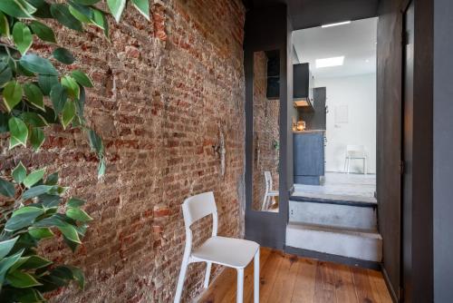 a room with a brick wall and a white chair at Charming Two-Bedroom River Side Apartment in Antwerp