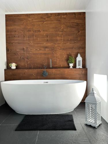 eine Badewanne im Bad mit einer Holzwand in der Unterkunft Cardos Villa in Grândola