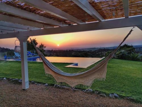 eine Hängematte auf einer Terrasse mit Sonnenuntergang im Hintergrund in der Unterkunft Cardos Villa in Grândola