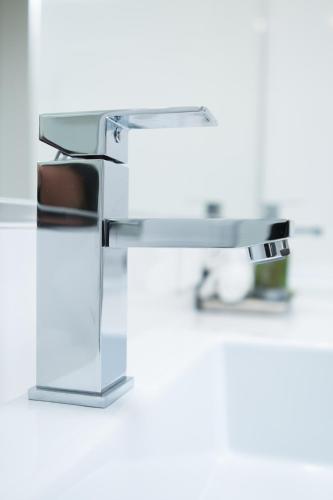 a white bathroom sink with a brown chair under it at Altitude Motel Apartments in Toowoomba