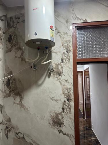 a bathroom with a marble wall with a water heater at PG for girls in New Delhi